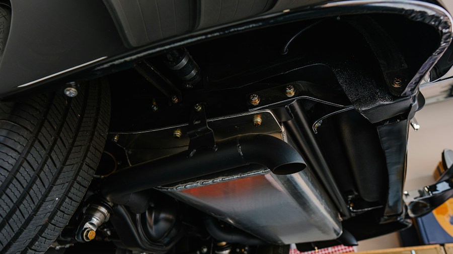 Curb Feelers Were a Car Accessory Essential in the 1980s Here's Why They Disappeared 1 mechanic installing car parts undercarriage
